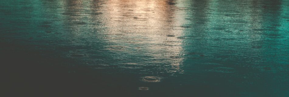 Water with orange, blue, and turquoise light reflected on it